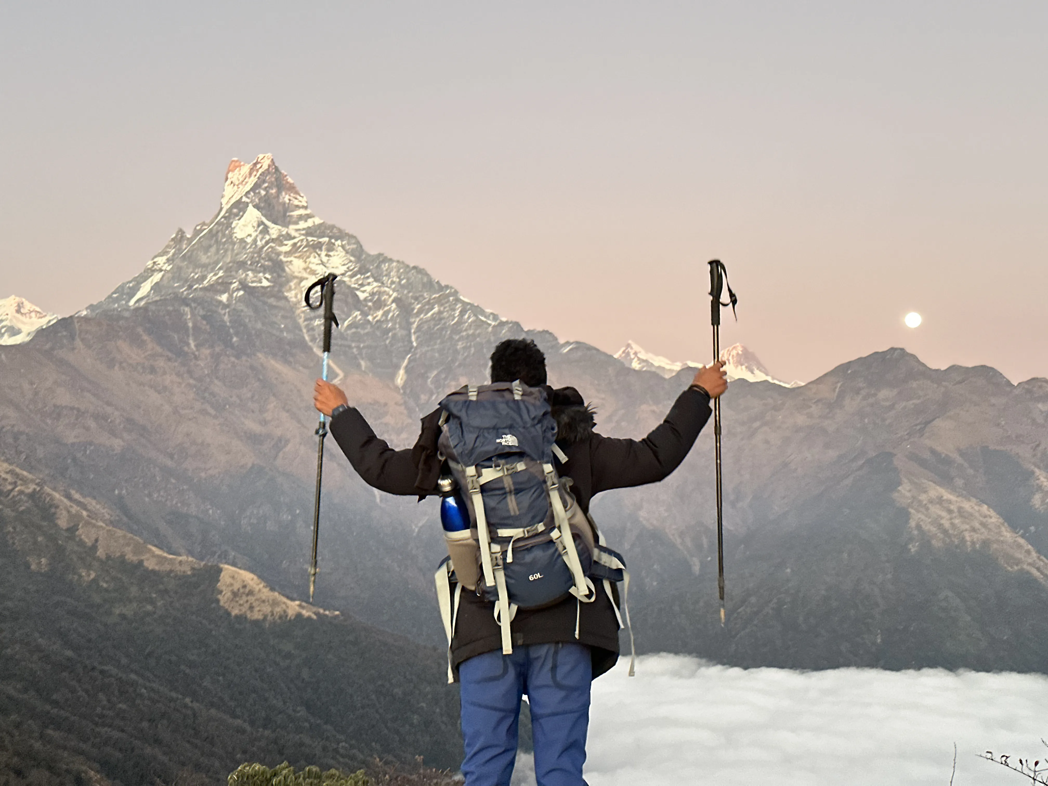 Trekker with poles raised, Machhapuchhre behind